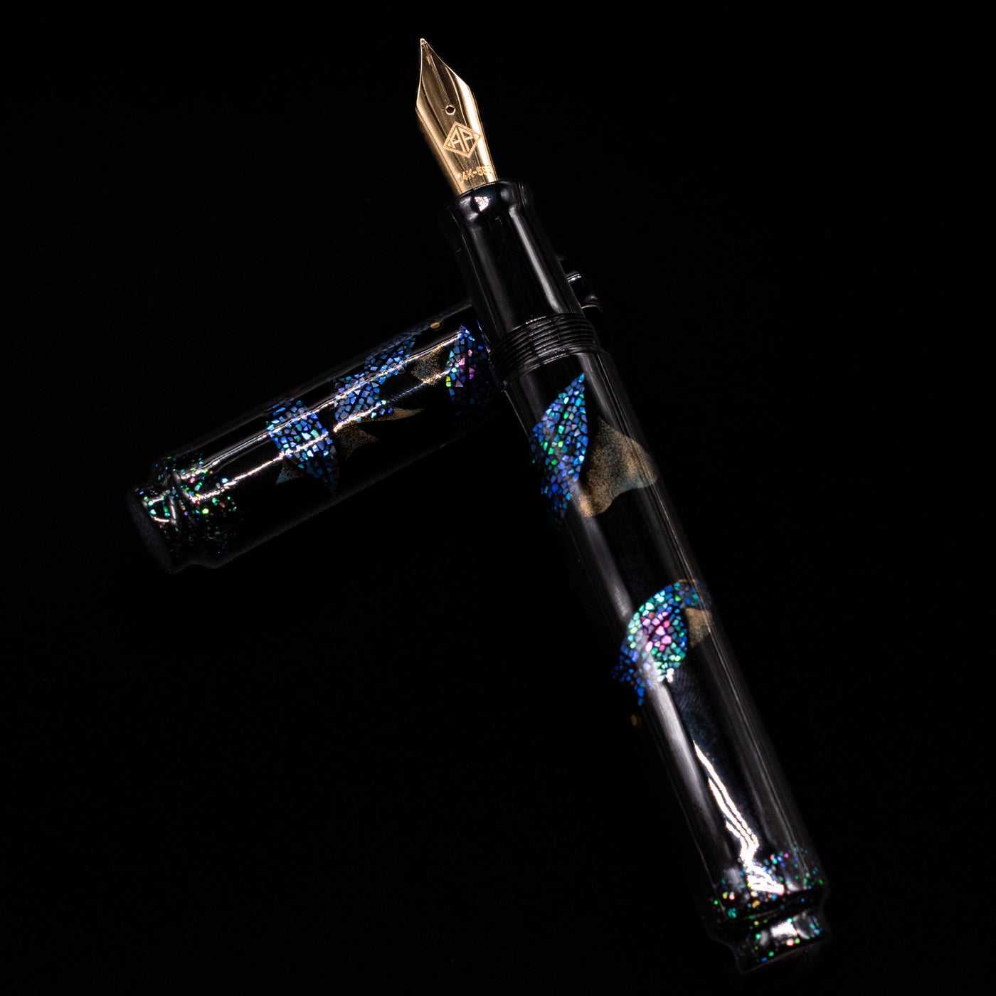 AP Limited Editions Writer Maki-e Fountain Pen - The Firefly Squid laying on top of its cap in a crossed position showing full view of the entire uncapped pen.