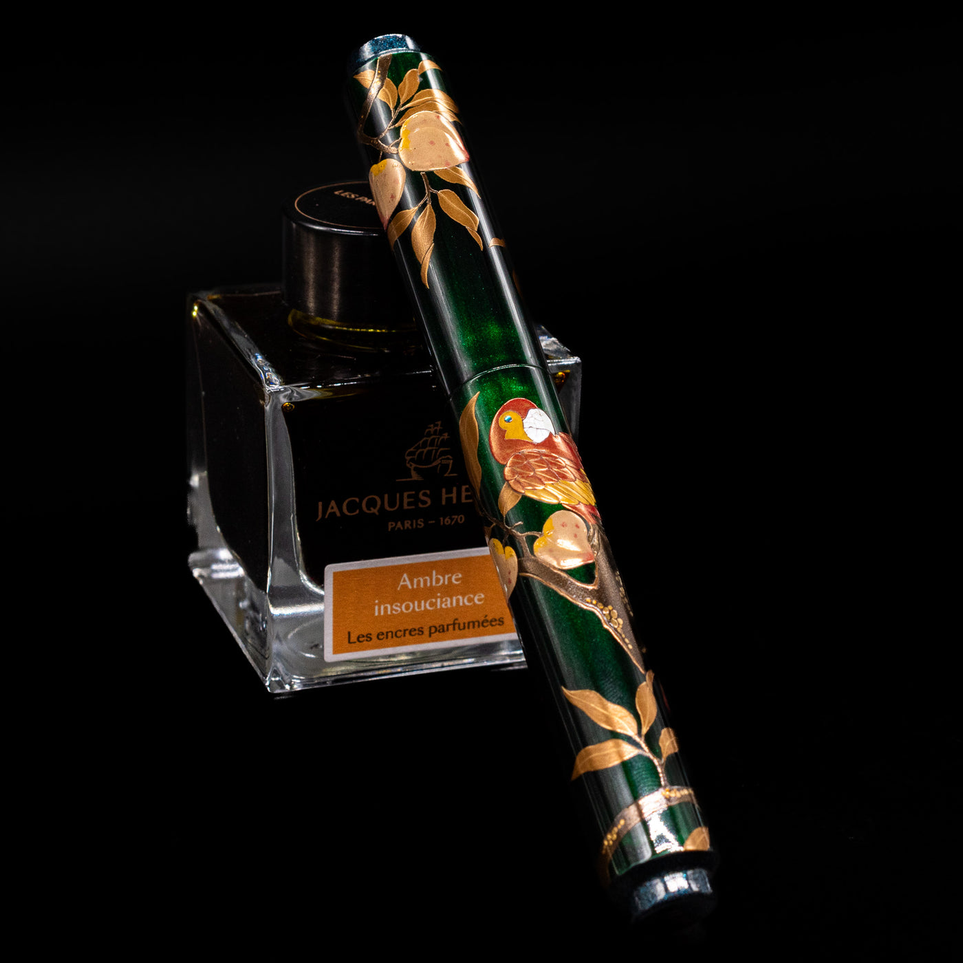 AP Limited Editions Writer Maki-e Fountain Pen - The Parrot with Peaches capped, leaning against an ink bottle. 