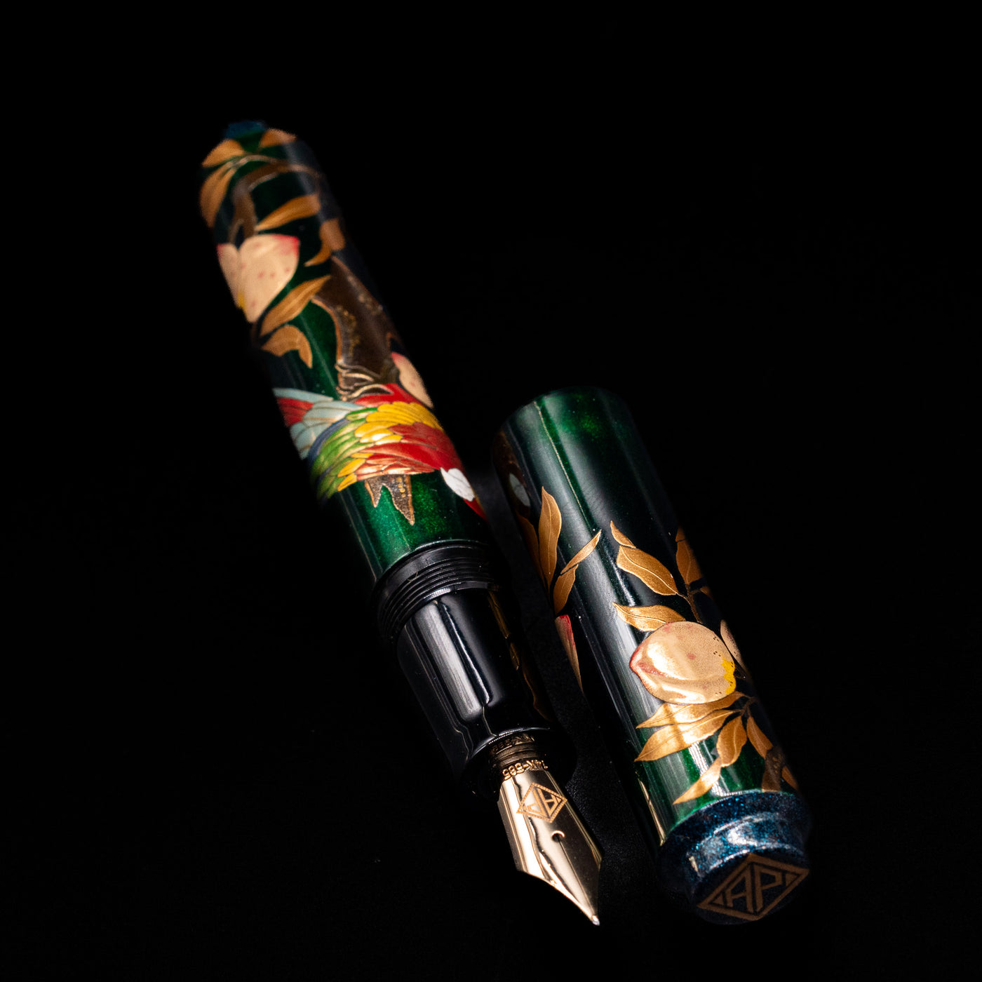 A full view of the AP Limited Editions Writer Maki-e Fountain Pen - The Parrot with Peaches uncapped, with its cap laying next to the pen. 