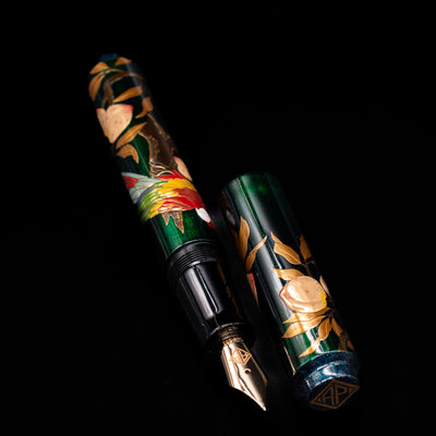 A full view of the AP Limited Editions Writer Maki-e Fountain Pen - The Parrot with Peaches uncapped, with its cap laying next to the pen. 
