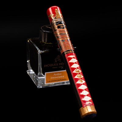 AP Limited Editions Writer Maki-e Fountain Pen - The Pride of Samurai capped, leaning against an ink bottle. 