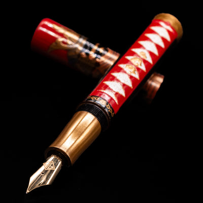 AP Limited Editions Writer Maki-e Fountain Pen - The Pride of Samurai laying across its own cap, crossed, with a focus on the nib.
