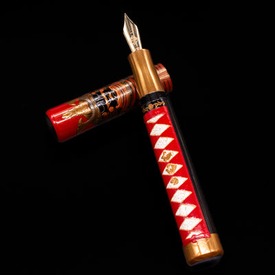AP Limited Editions Writer Maki-e Fountain Pen - The Pride of Samurai laying on top of its cap in a crossed position showing full view of the entire uncapped pen.