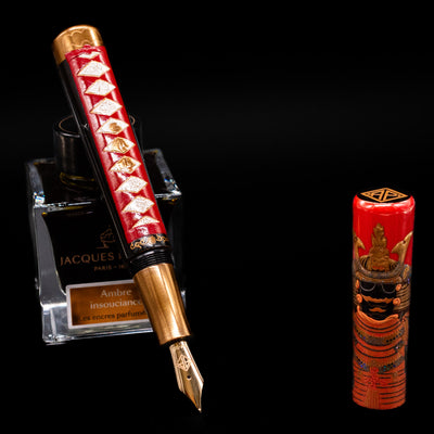 AP Limited Editions Writer Maki-e Fountain Pen - The Pride of Samurai leaning on an ink bottle uncapped showcasing the detailing on the nib.