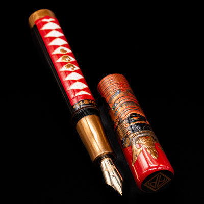 A full view of the AP Limited Editions Writer Maki-e Fountain Pen - The Pride of Samurai uncapped, with its cap laying next to the pen. 