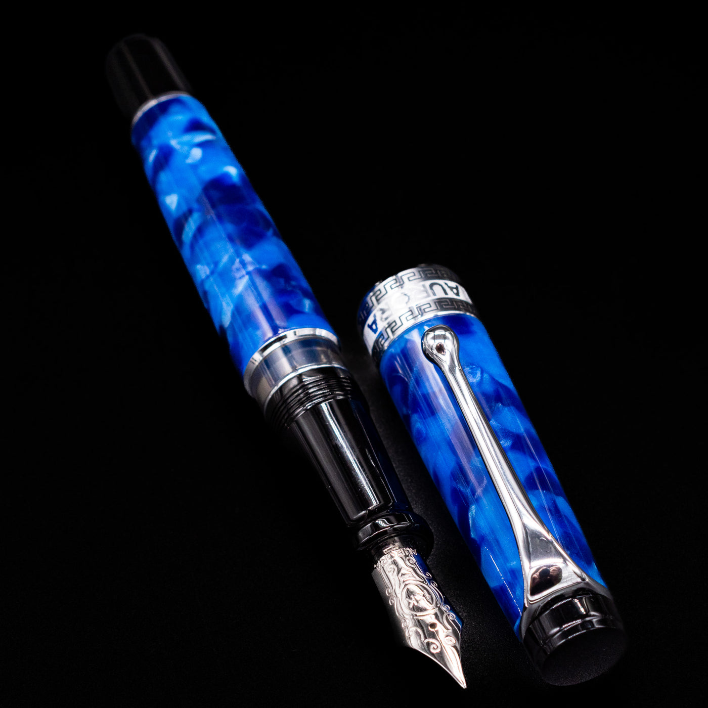 Aurora Optima Auroloide Blue & Chrome fountain pen displayed uncapped, revealing the marbled blue resin barrel, rhodium-plated grip section, and engraved nib.