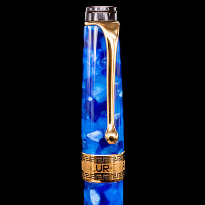 Close-up of the cap and clip of the Aurora Optima Auroloide Blue & Gold fountain pen, highlighting the polished gold-plated clip, decorative engraved cap band, and the rich marbled blue resin finish.