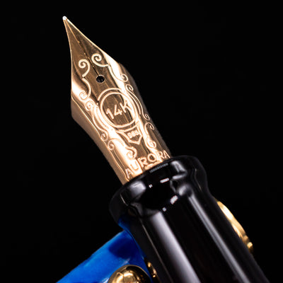 Close-up of the gold 14k nib on the Aurora Optima Auroloide Blue & Gold fountain pen, showing fine engravings and the Aurora logo.