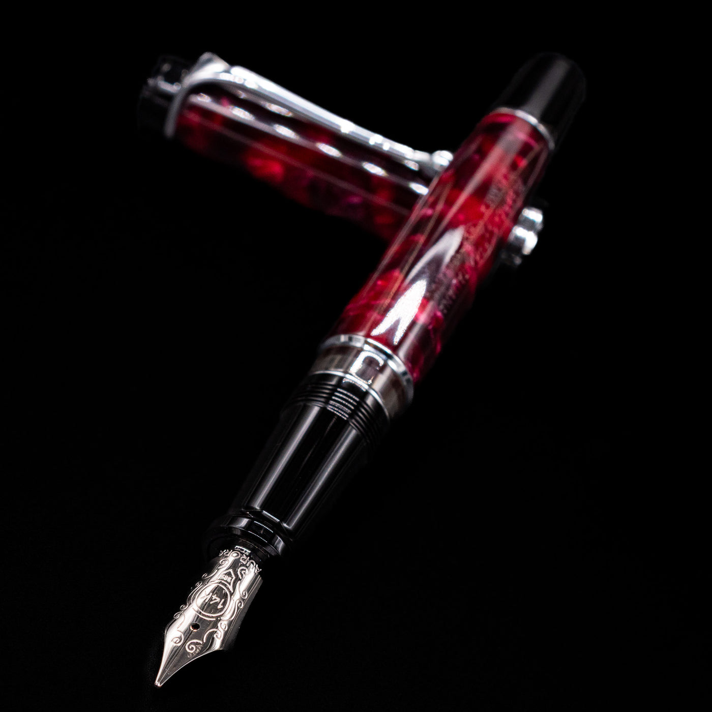Aurora Optima Auroloide Burgundy fountain pen and cap crossed, with focus on the engraved gold nib and the deep marbled burgundy resin.