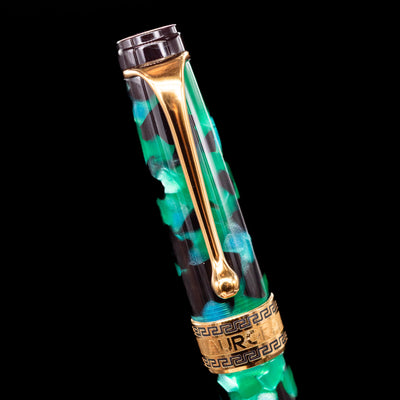 Close-up of the cap and clip of the Aurora Optima Auroloide Emerald Green fountain pen, highlighting the polished gold-plated clip, decorative engraved cap band, and the vibrant marbled green resin finish.