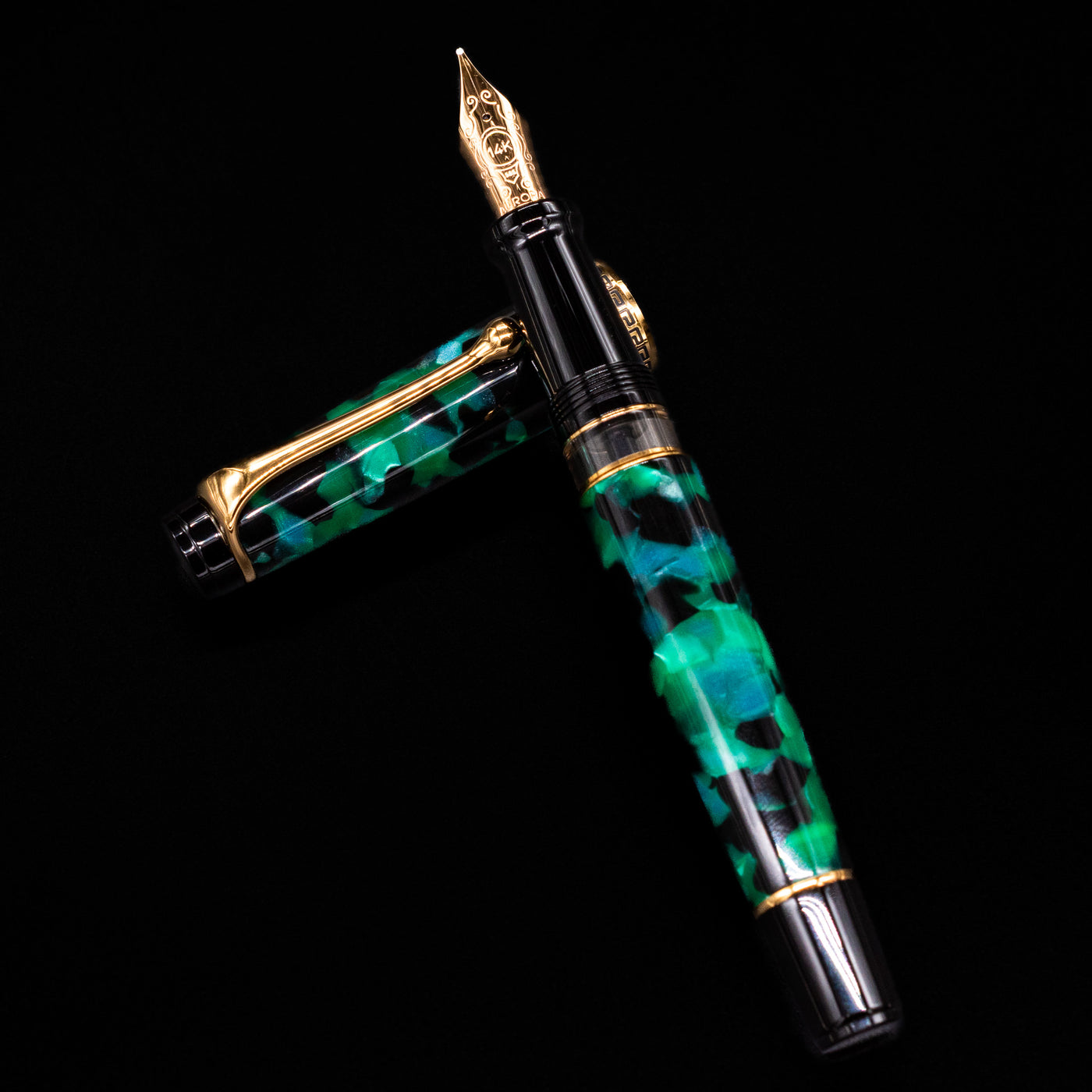 Aurora Optima Auroloide Emerald Green fountain pen and cap arranged in a crossed position, showcasing the elegant marbled green finish, engraved cap band, and gold-plated clip.