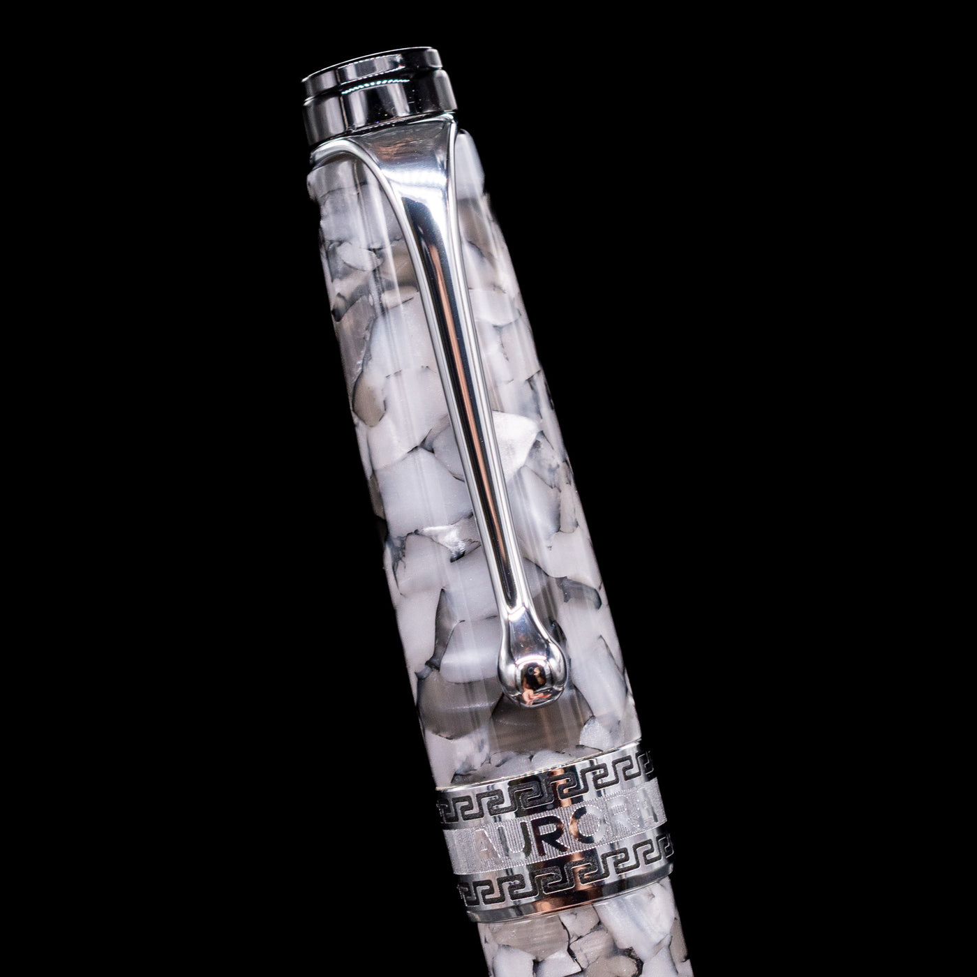 Close-up of the cap and clip of the Aurora Optima Auroloide Nero Perla fountain pen, highlighting the polished rhodium-plated clip, decorative engraved cap band, and the sophisticated marbled black-and-grey resin finish.