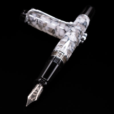 Aurora Optima Auroloide Nero Perla fountain pen and cap crossed, with focus on the engraved nib and the sleek marbled black-and-grey resin.