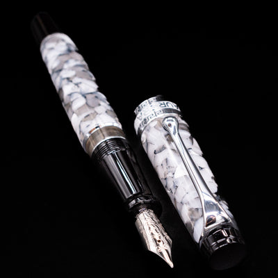Aurora Optima Auroloide Nero Perla fountain pen displayed uncapped, revealing the marbled black-and-grey resin barrel, grip section, and engraved nib.