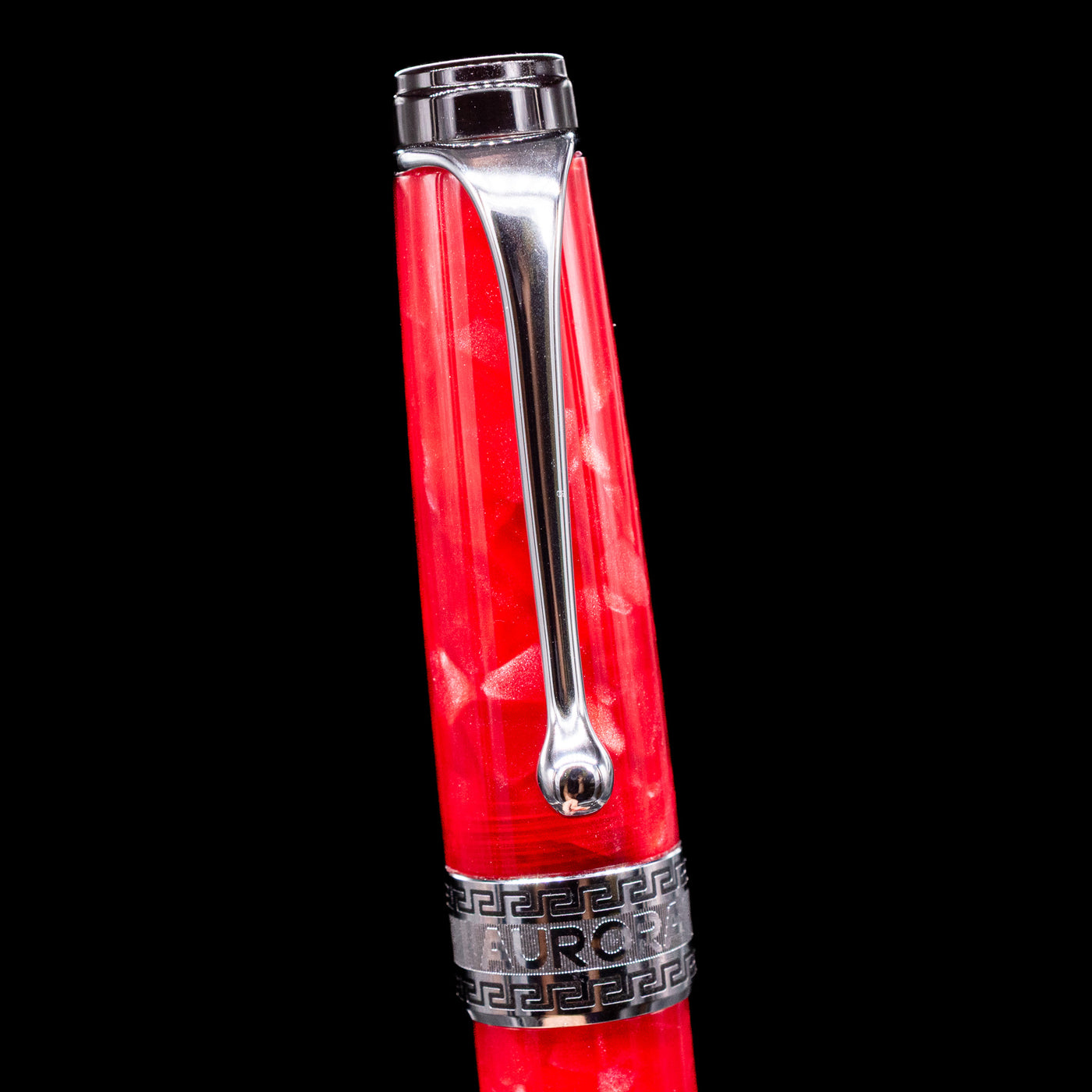 Close-up of the cap and clip of the Aurora Optima Auroloide Rossa fountain pen, highlighting the polished rhodium-plated clip, decorative engraved cap band, and the rich marbled red resin finish.