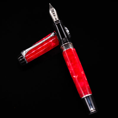 Aurora Optima Auroloide Rossa fountain pen and cap arranged in a crossed position, showcasing the deep marbled red finish, engraved cap band, and silver clip.
