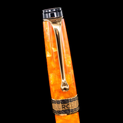 Close-up of the cap and clip of the Aurora Optima Orange fountain pen, highlighting the polished gold-plated clip, decorative engraved cap band, and the marbled orange resin finish.