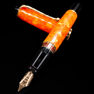 Aurora Optima Orange fountain pen and cap crossed, with focus on the engraved nib and the vibrant marbled orange resin.