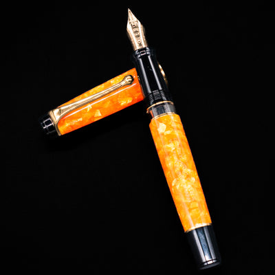 Aurora Optima Orange fountain pen and cap arranged in a crossed position, showcasing the rich marbled orange finish, decorative cap band, and gold-plated clip.