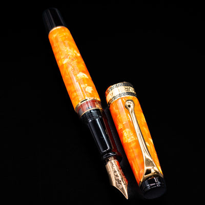 Aurora Optima Orange fountain pen displayed uncapped, revealing the marbled orange resin barrel, grip section, and engraved gold nib.