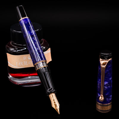 Aurora Optima Viola fountain pen displayed uncapped, leaning on an ink bottle to reveal its rhodium-plated 14k gold nib. The marbled purple resin barrel contrasts beautifully with the polished rose gold trim.
