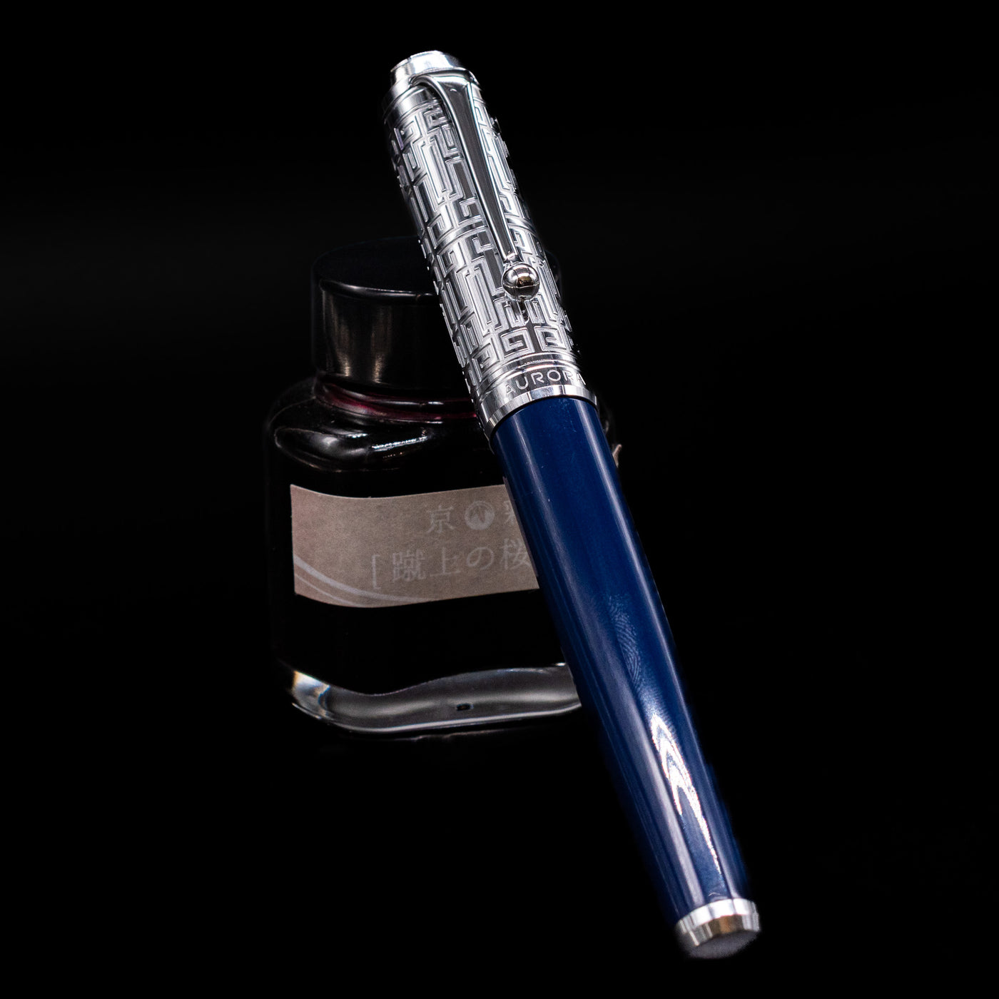 Aurora Talentum Dedalo Blue Fountain Pen - Preowned capped, leaning against an ink bottle. 