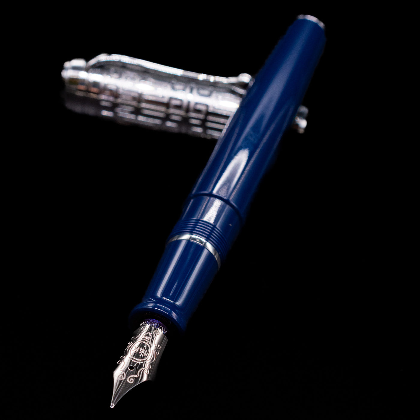 Aurora Talentum Dedalo Blue Fountain Pen - Preowned laying across its own cap, crossed, with a focus on the nib.