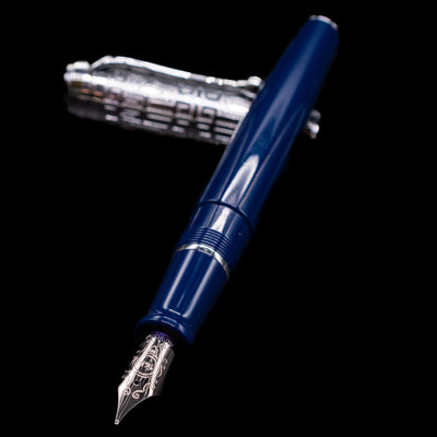 Aurora Talentum Dedalo Blue Fountain Pen - Preowned laying across its own cap, crossed, with a focus on the nib.