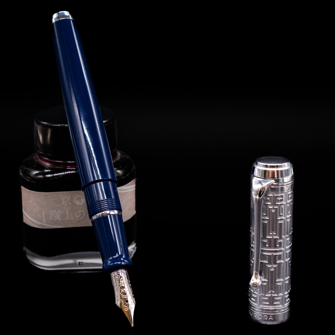 Aurora Talentum Dedalo Blue Fountain Pen - Preowned leaning on an ink bottle uncapped showcasing the detailing on the nib.