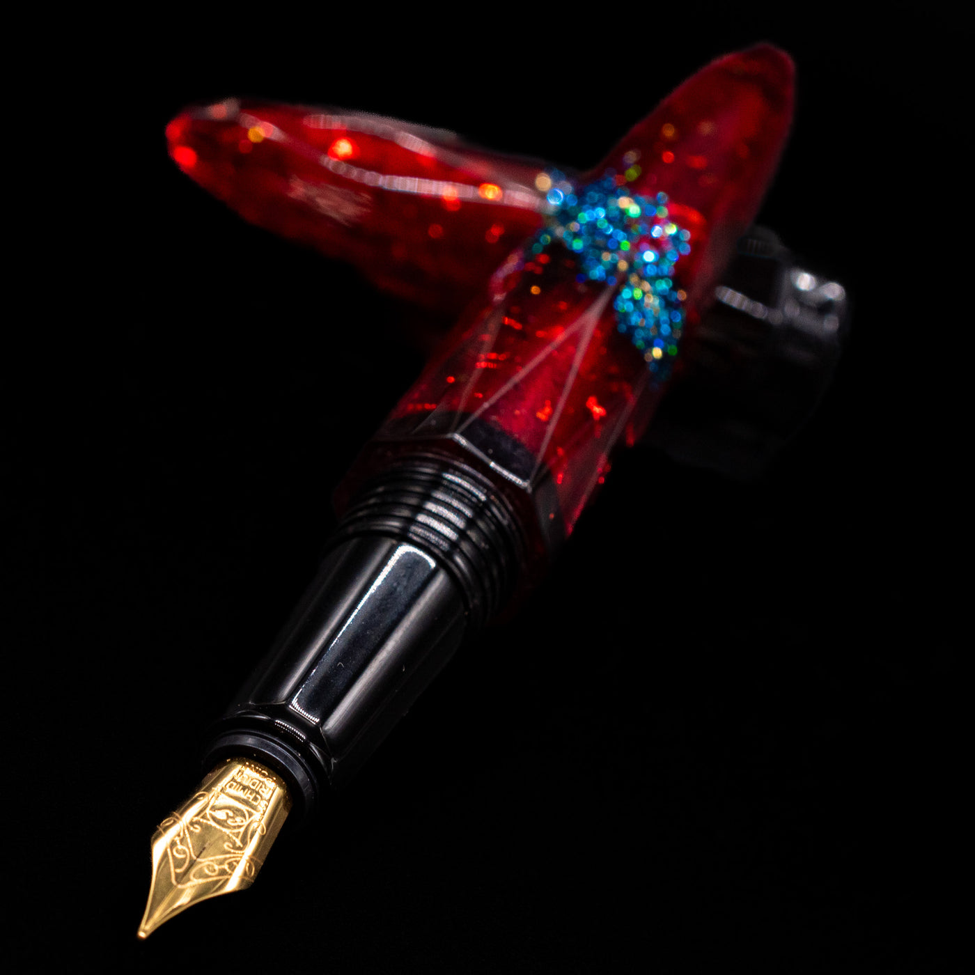 BENU Briolette Fountain Pen - Ruby Forest laying across its own cap, crossed, with a focus on the nib.
