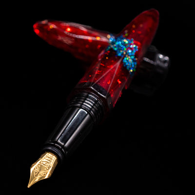 BENU Briolette Fountain Pen - Ruby Forest laying across its own cap, crossed, with a focus on the nib.
