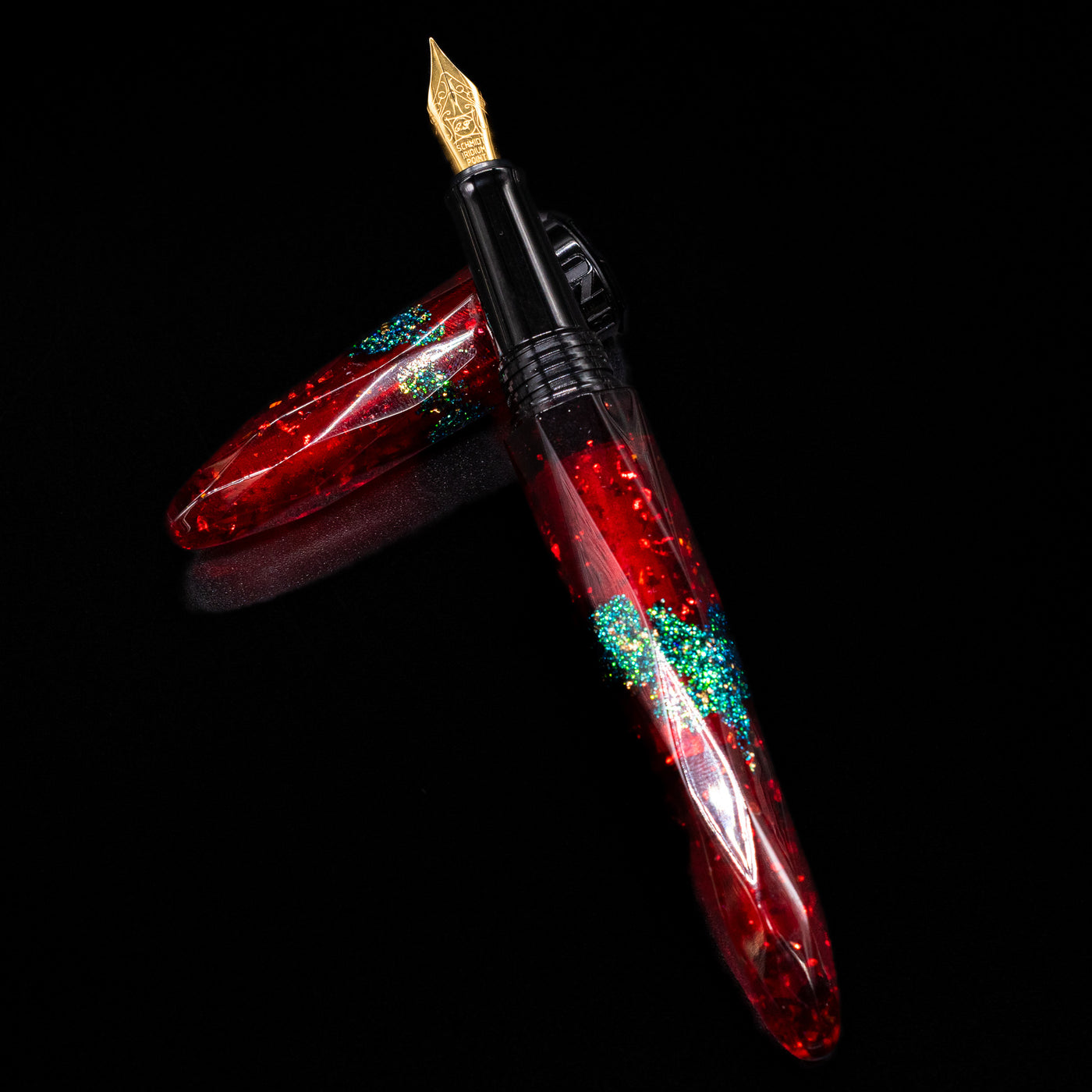 BENU Briolette Fountain Pen - Ruby Forest laying on top of its cap in a crossed position showing full view of the entire uncapped pen.