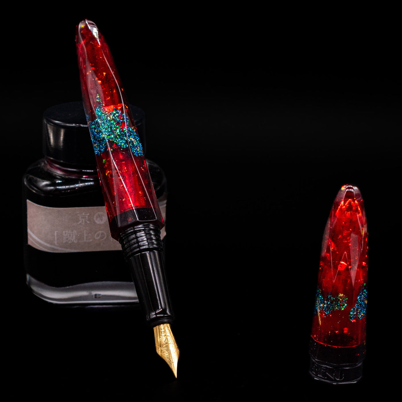 BENU Briolette Fountain Pen - Ruby Forest leaning on an ink bottle uncapped showcasing the detailing on the nib.