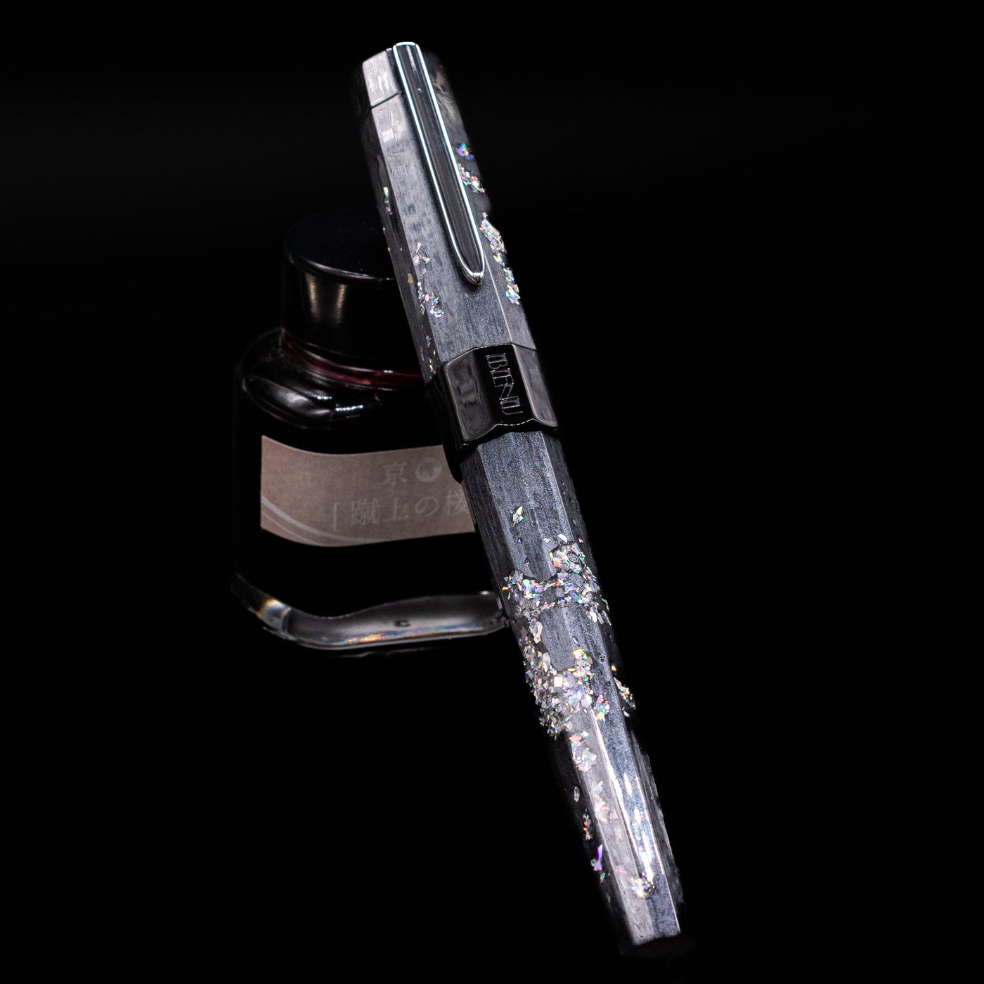 BENU Euphoria Caviar Fountain Pen capped, leaning against an ink bottle. 