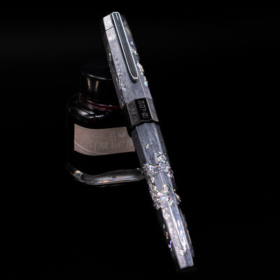BENU Euphoria Caviar Fountain Pen capped, leaning against an ink bottle. 