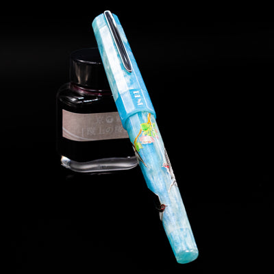 BENU Euphoria Limited Edition Fountain Pen - Swallow’s Song capped, leaning against an ink bottle. 