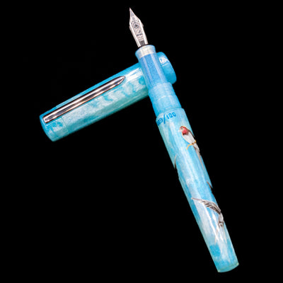 BENU Euphoria Limited Edition Fountain Pen - Swallow’s Song laying on top of its cap in a crossed position showing full view of the entire uncapped pen.