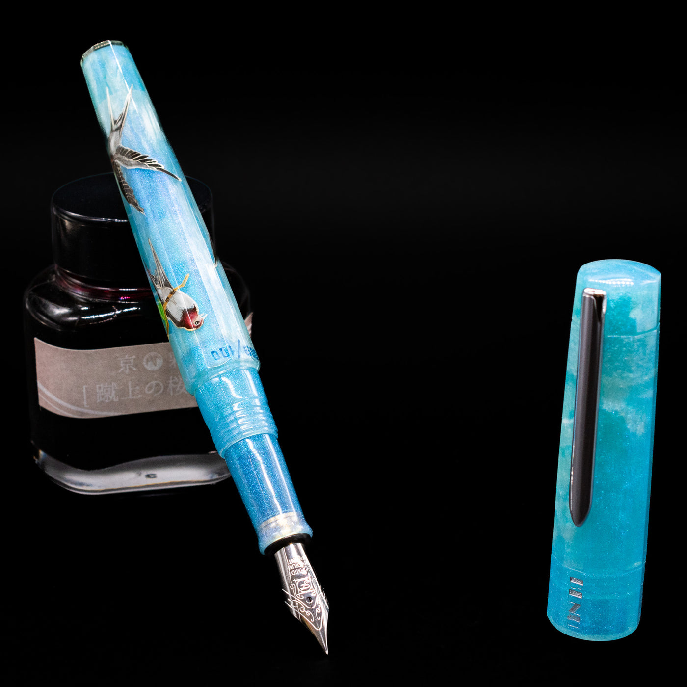 BENU Euphoria Limited Edition Fountain Pen - Swallow’s Song leaning on an ink bottle uncapped showcasing the detailing on the nib.