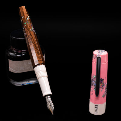 BENU Euphoria Neapolitan Ice Cream Fountain Pen - Preowned leaning on an ink bottle uncapped showcasing the detailing on the nib.