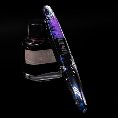 BENU Happy Chameleon Fountain Pen capped, leaning against an ink bottle. 