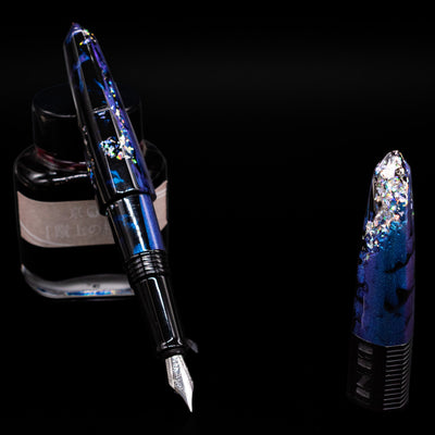 BENU Happy Chameleon Fountain Pen leaning on an ink bottle uncapped showcasing the detailing on the nib.