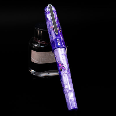 BENU Talisman Limited Edition Fountain Pen - Lavender capped, leaning against an ink bottle. 