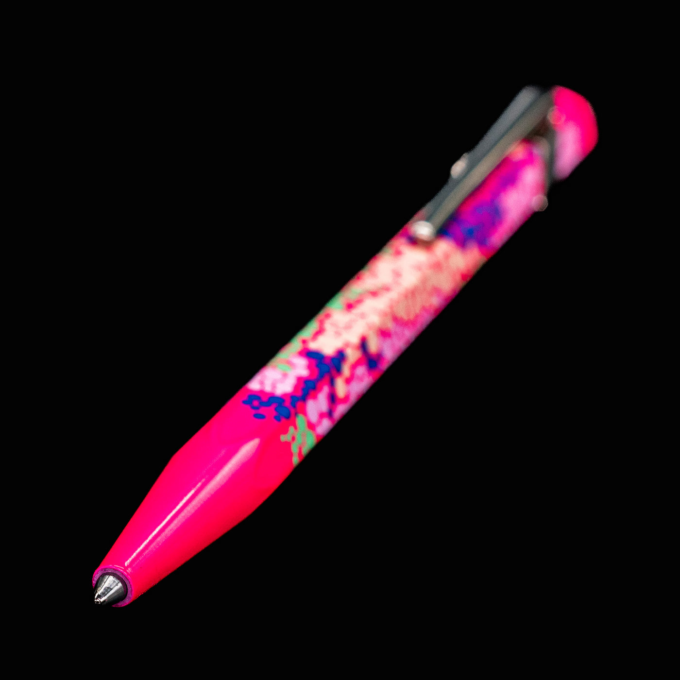Full view of the Caran d’Ache 849 Special Edition Germanier Fluo Pink ballpoint pen with the writing tip extended, highlighting the vivid neon pink finish, hexagonal profile, and polished silver clip.
