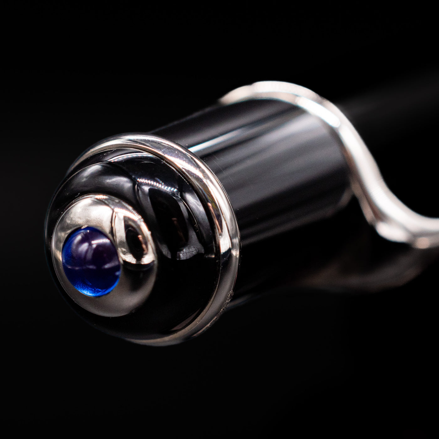 Zoomed-in view of the top of the cap with the iconic blue jewel for the Cartier Diabolo Black & Platinum Ballpoint Pen - Preowned.