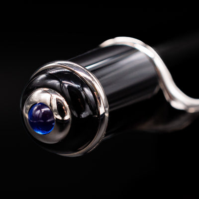 Zoomed-in view of the top of the cap with the iconic blue jewel for the Cartier Diabolo Black & Platinum Ballpoint Pen - Preowned.