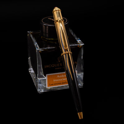 Cartier Diabolo Mini Flame Ballpoint Pen - Preowned leaning on an ink bottle.