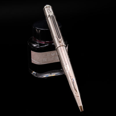 Cartier Diabolo Platinum Double C Logo Ballpoint Pen - Preowned leaning on an ink bottle.