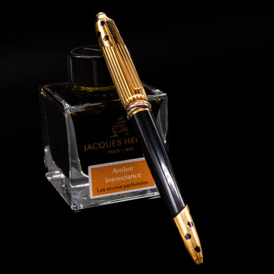 Cartier Panthere Black Lacquer Ballpoint Pen - Preowned leaning on an ink bottle.