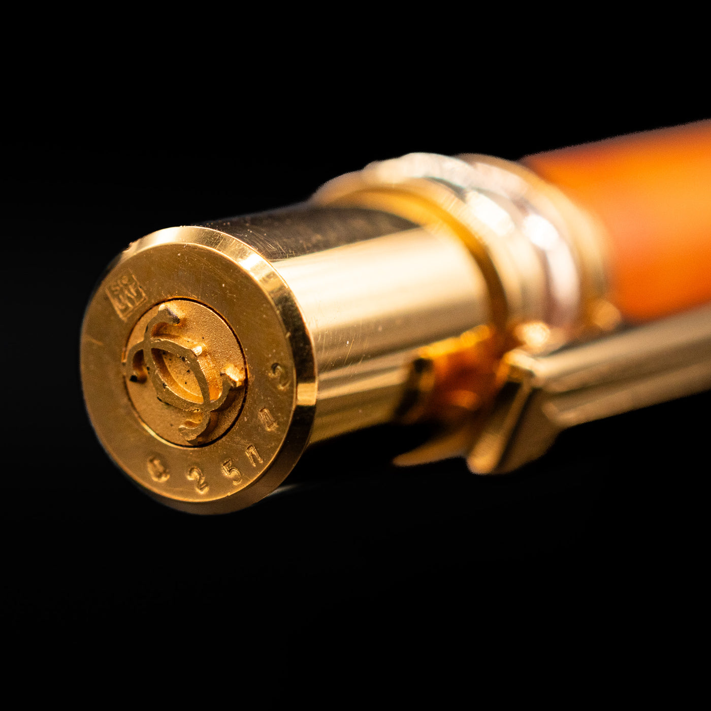 A zoomed-in view of the top of the cap, and the finial on the Cartier Trinity Orange Mechanical Pencil - Preowned.