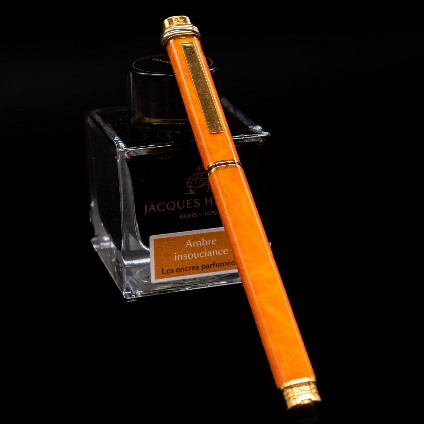 Cartier Vendome Oval Orange Fineliner Pen - Preowned capped, leaning against an ink bottle. 